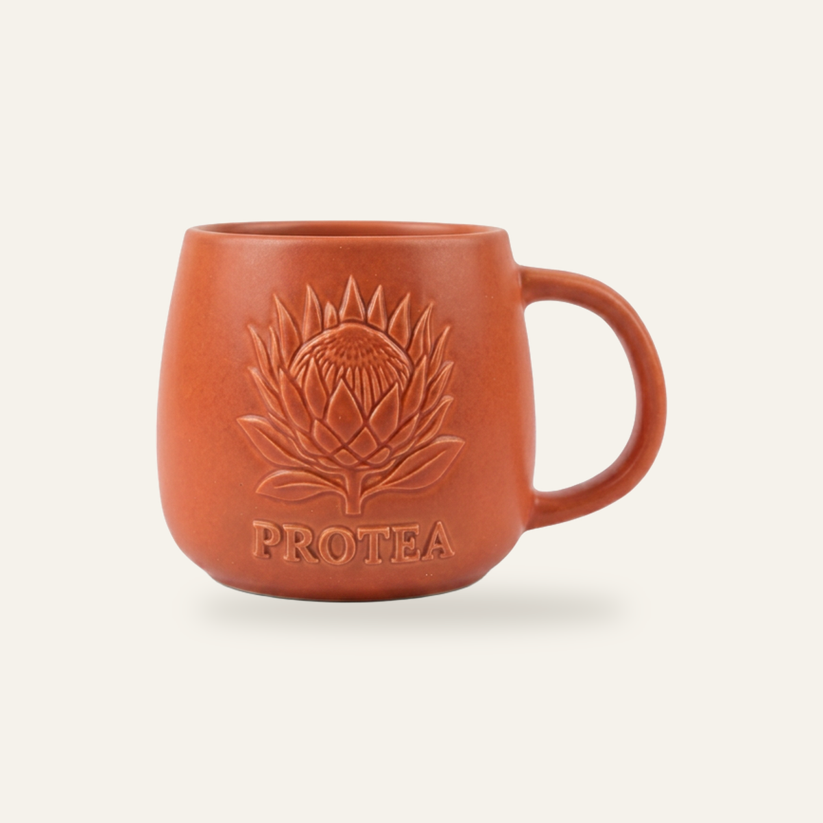 Terracotta stoneware mug photographed straight on, with a protea motif raised in relief off the surface in the same glaze as the body, so the mark reads as texture rather than colour