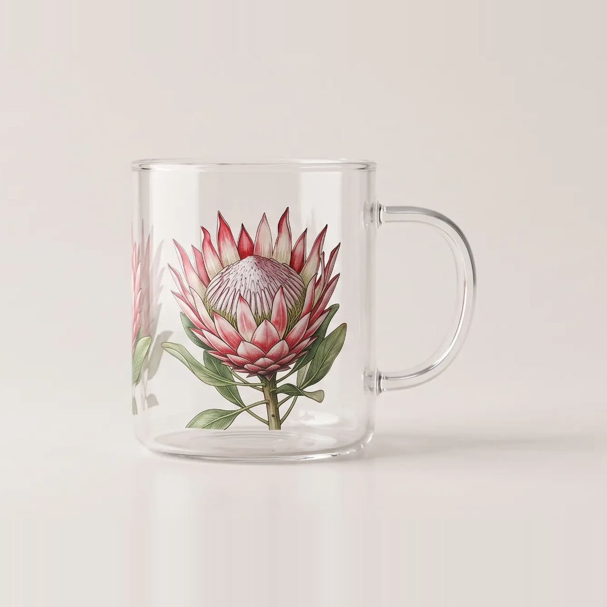 Clear glass mug printed with a full colour protea illustration in pink and green, fine detail visible through the glass